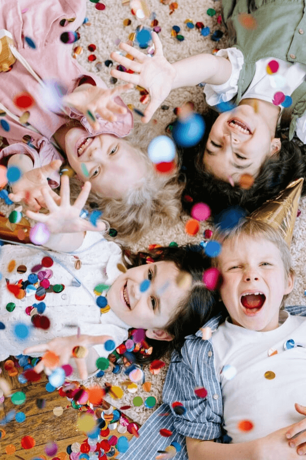 Children lying on floor smiling and catching confetti