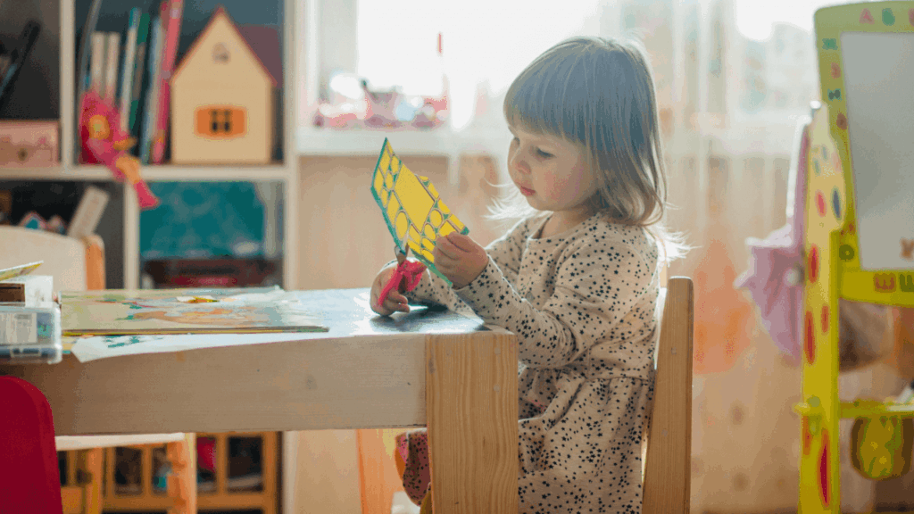Young girl cutting colorful paper with scissors