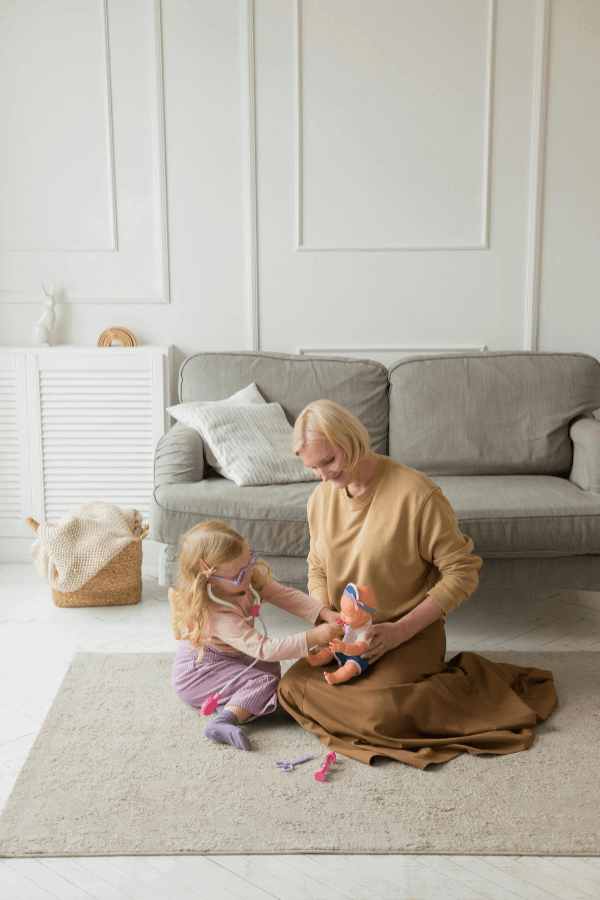Woman and young girl playing doctor with baby doll