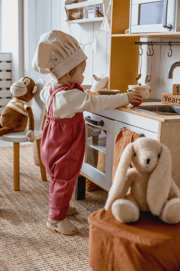 Child with chef hat in play kitchen